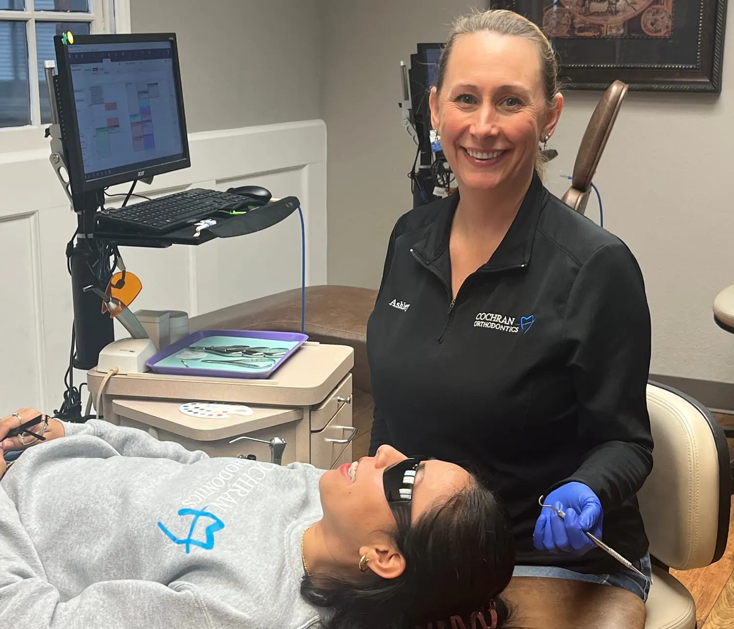 A Cochran Orthodontics team member treating a smiling patient in the chair