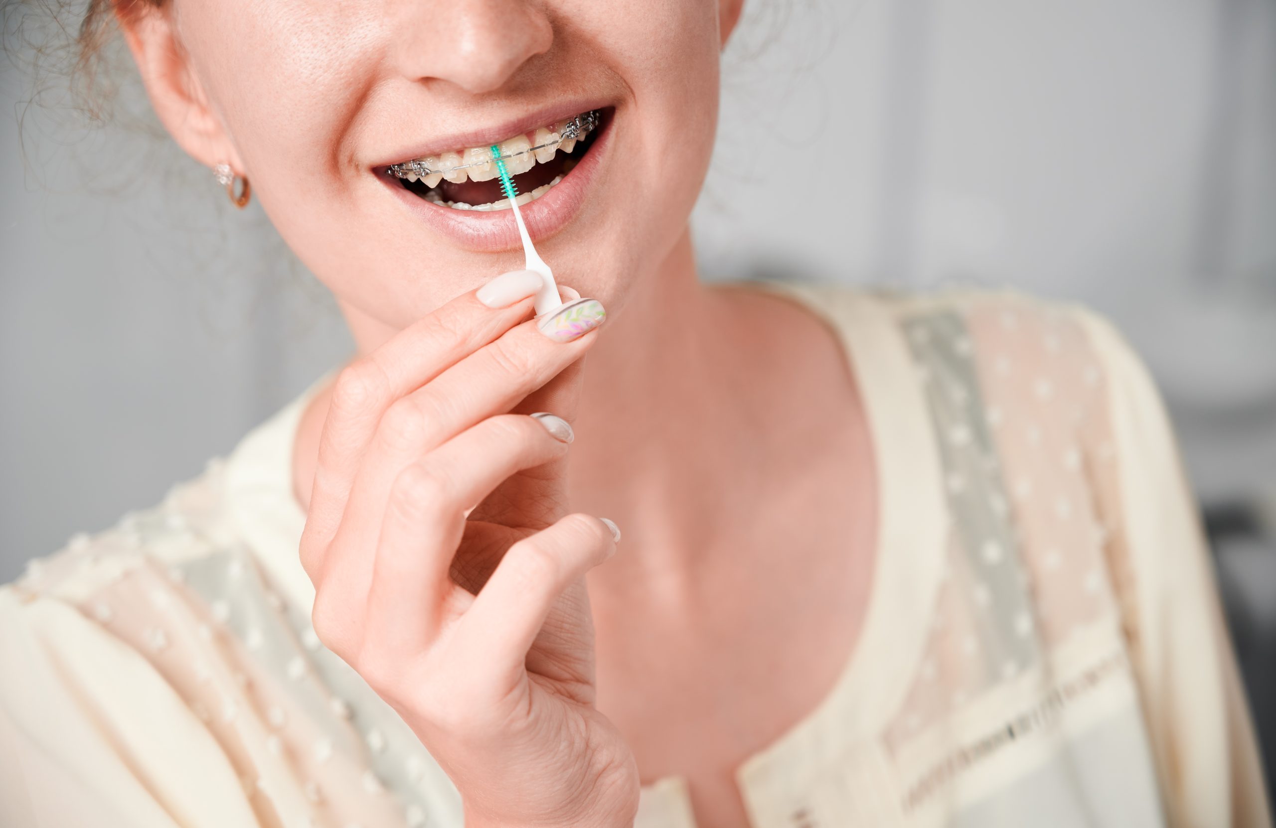 Smiling woman medic with braces with great teeth holding tooth brush, isolated on white background